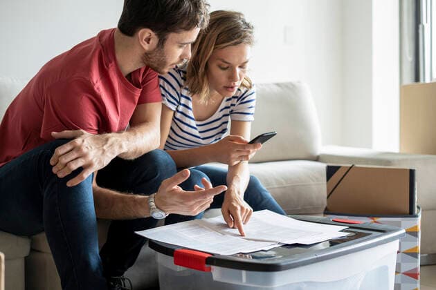 Young couple reading documents in their new house Copyright: FrédéricxCirou B75385333