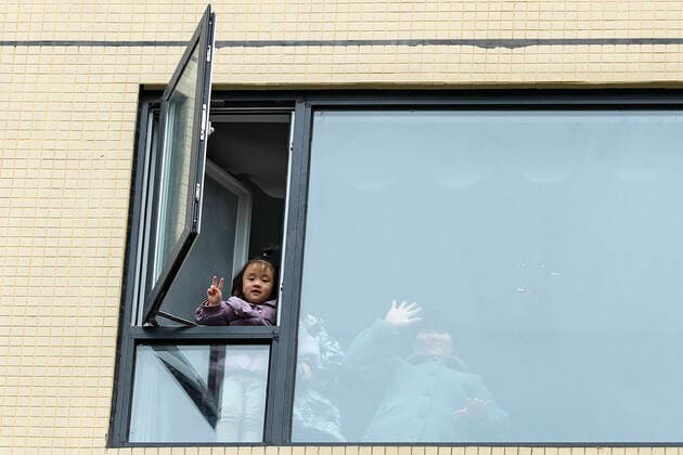 (210106) -- BEIJING, Jan. 6, 2021 -- A girl makes a V sign from her home at a quarantined residential community in Chenghua District of Chengdu, southwest China s Sichuan Province, Dec. 10, 2020. ) XINHUA-PICTURES OF THE YEAR 2020-CHINA S FIGHT AGAINST COVID-19 ShenxBohan 