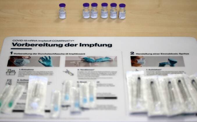 Covid-19-Impfung 07.01.2021, Erfurt, in einem Seniorenheim wird heute der Belegschaft und den Senioren die 1.Impfung mit dem COVID-19 mRNA-Impfstoff Comirnaty der Firma BioNtech Pfizer verabreicht, in einem Fläschchen sind 5 Impfdosen im Bild: Informationsblatt zur Vorbereitung der Impfung, darauf liegen Spritzen, dahinter steht der Impfstoff in Flaschen