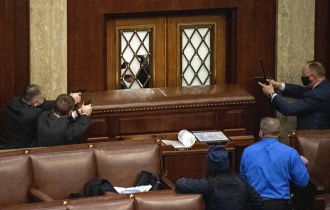 Plain clothes Capitol Police point their guns at rioters who had broken the glass of the main door of the House Chamber that was reinforced with a large piece of furniture at the U.S. Capitol in Washington, DC on Wednesday, January 6, 2021. The congress members were being evacuated at this time. Shots did ring out near this door and one rioter was killed, before the assault on the police and the House Chamber was stopped. A pro-Trump mob broke into the U.S. Capitol causing destruction, an evacuation and at least four deaths. After a long delay Congress certified Joe Biden s victory in the Presidential election.  WAS20210109152 PatxBenic