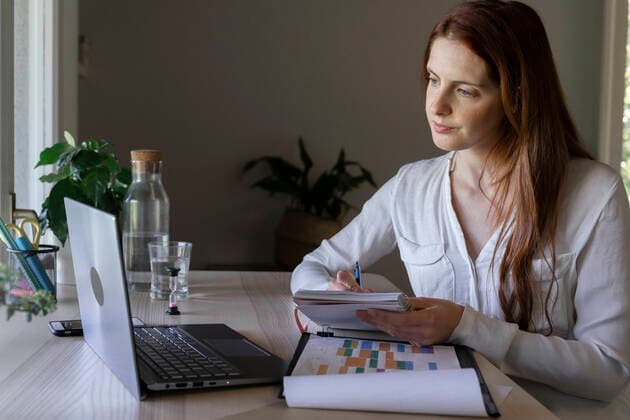 Psychologist writing in book while working on laptop at home model released Symbolfoto property released AFVF07432