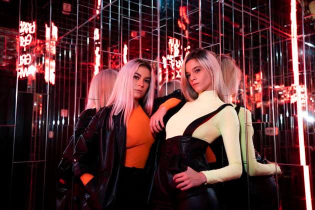 Beautiful female friends standing in red light room model released Symbolfoto DAMF00604