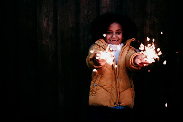 Creative Highlights Symbolbilder Smiling girl standing and playing with sparkler at night model released Symbolfoto EBBF01446