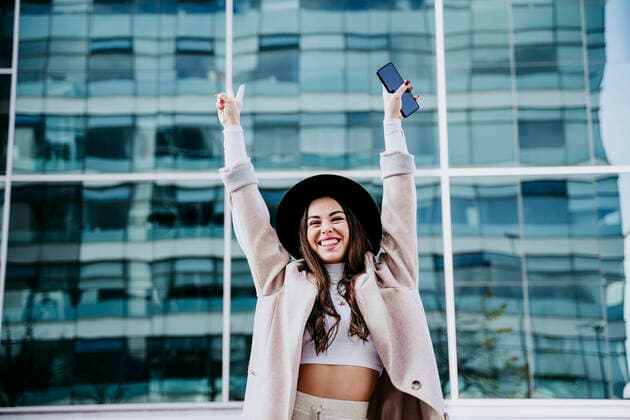 Creative Highlights Symbolbilder Smiling woman gesturing peace sign while standing against building in city model released Symbolfoto EBBF01481