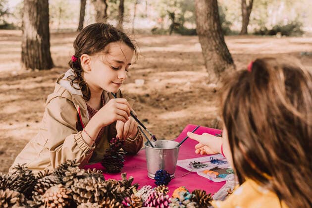 Cute sisters coloring while sitting with pine cones at picnic table in park model released Symbolfoto ERRF04628