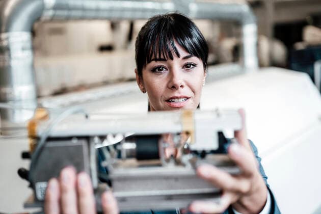 Businesswoman investigating while looking at machine part in industry model released Symbolfoto property released JOSEF02158