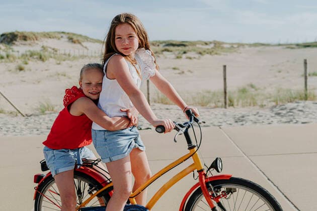 IMAGO Creative: Schwesternschaft Younger sister embracing girl while sitting on bicycle during sunny day model released Symbolfoto OGF00609