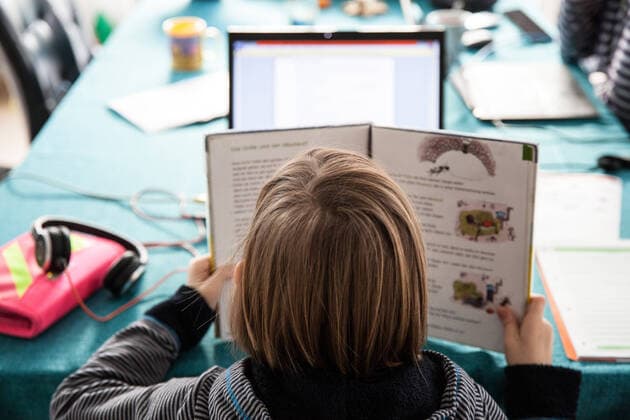 Bamberg, Deutschland 13. Januar 2021: Ein Schulkind hat ein Schulbuch in der Hand, sitzt an einem Tisch und macht Hausaufgaben im Homeschooling. Auf dem Tisch steht ein aufgeklappter Laptop für den Onlineunterricht. Bayern *** Bamberg, Germany 13 January 2021 A schoolchild holds a textbook, sits at a table and does homeschooling homework On the table is an unfolded laptop for online instruction Bavaria Copyright: xFotostandx xK.xSchmittx