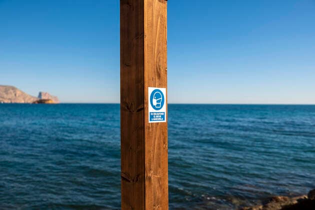 20.01.2021, Altea, Alicante, Spanien, Pictogramm eines Kopfes mit Mundschutz und der Hinweis Es obligatorio el uso de la mascarilla: Die Verwendung der Maske ist obligatorisch weisen auf die Covid-19 Hygieneregeln am Strand hin.