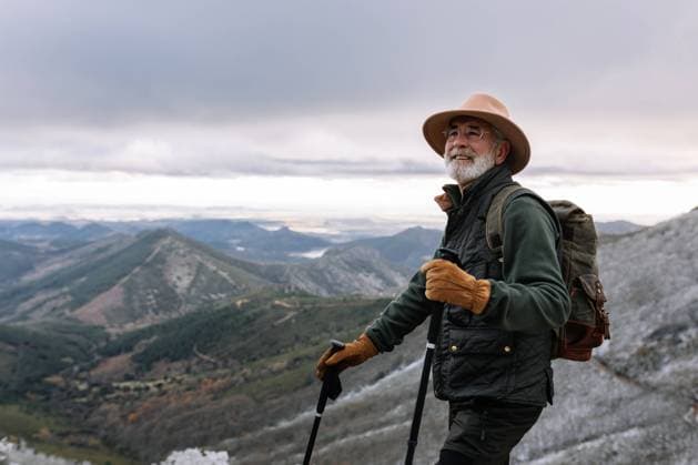 IMAGO Creative: Wintersport, Mode Delighted senior male traveler in warm clothes and with trekking poles standing in highlands and looking away during vacation in Caceres Copyright: xSergioxVictorxVegax Model Released