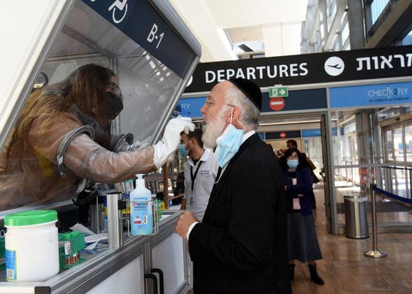 A worker collects a swab sample from an Orthodox traveler at a CHECK 2 FLY rapid coronavirus testing booth in Israel s Ben Gurion Airport in Lod, near Tel Aviv, on Sunday, January 24, 2021.  JER2021012401 DEBBIExHILL