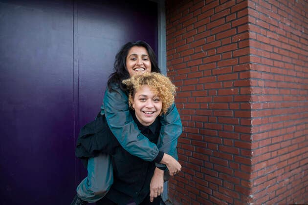 Creative Highlights Symbolbilder Young woman piggybacking girlfriend in front of building entrance model released Symbolfoto AXHF00093