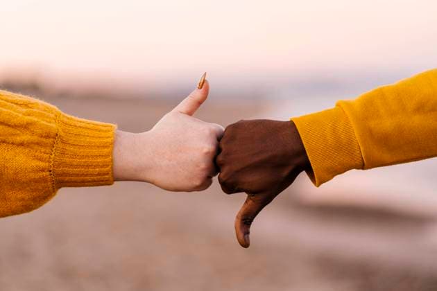 Creative Highlights Symbolbilder Man and woman gesturing with thumps up and down at beach model released Symbolfoto EGAF01401