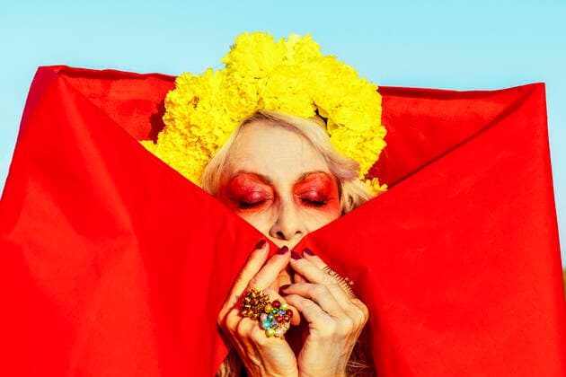 IMAGO Creative: Clickbait, Modetrends Senior woman with eyes closed wearing marigold flowers on sunny day model released Symbolfoto ERRF04852