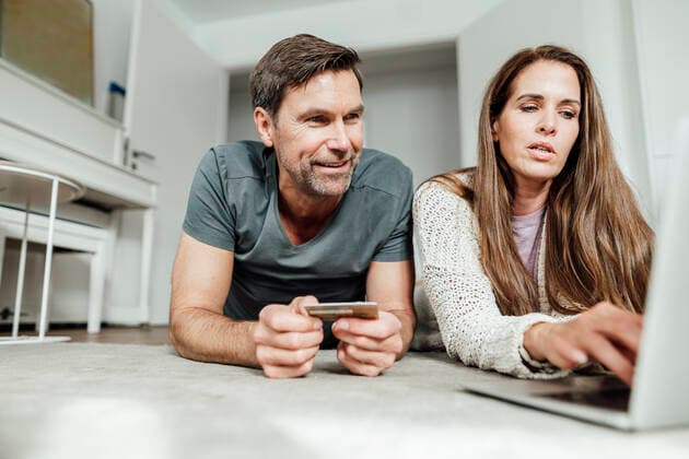 Mature woman paying by credit card though laptop with man at home model released Symbolfoto property released JOSEF02814