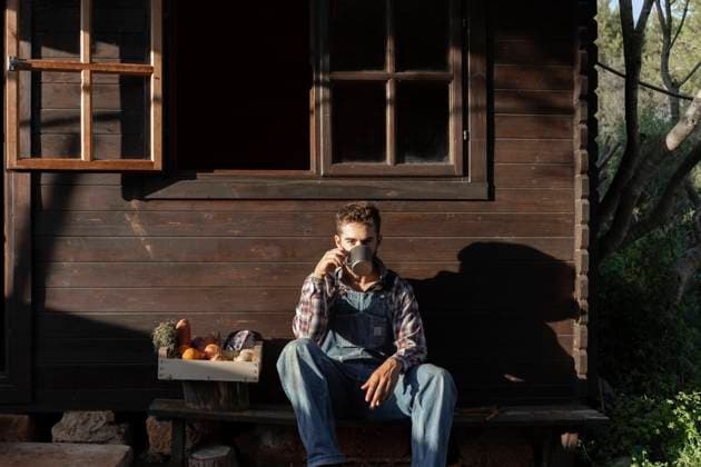 IMAGO Creative, Architektur, Zukunftsmodell Tiny house Male farmer with vegetable crate having coffee against wooden house on sunny day model released Symbolfoto property released JPTF00619
