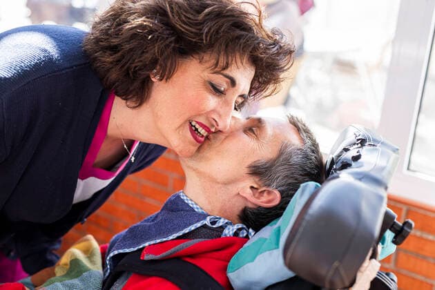 IMAGO Creative: NGO, Rehabilitation und Gesundheitswesen Disabled man kissing female nurse at nursing home model released Symbolfoto property released LJF02002