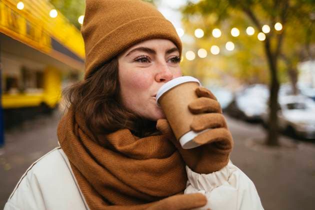 Young woman in warm clothing drinking coffee on street during autumn model released Symbolfoto OYF00306