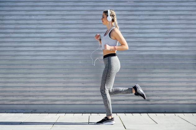 IMAGO Creative: Clickbait, Sport und Fitness Female athlete wearing headphones jogging against shutter model released Symbolfoto PGF00312