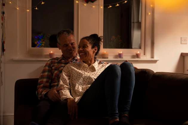 IMAGO Creative: Herbst, Gemütliches Zuhause Smiling couple talking while relaxing on sofa at home model released Symbolfoto property released PMF01733