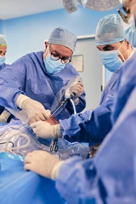 Mature doctor operating shoulder arthroscopic surgery with colleague while standing in operating room during COVID-19 model released Symbolfoto property released SASF00159