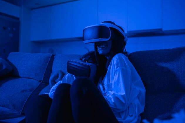 IMAGO Creative: 2022 Farbe des Jahres: Very Peri, Veilchenblau IMAGO Creative: Jahreszeit Winter, Couching Mother sitting with daughter using virtual reality glasses in blue illuminated room model released Symbolfoto property released SNF00927