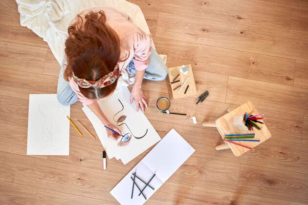Female artist drawing while sitting on floor in living room model released Symbolfoto property released VEGF03359