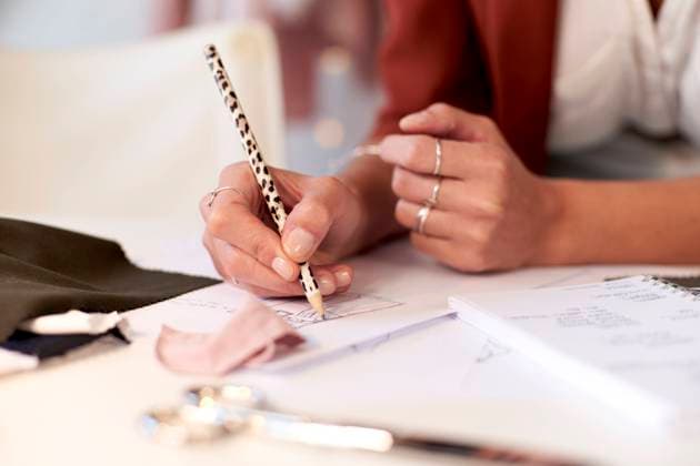 Female fashion professional drawing design on paper at desk in atelier model released Symbolfoto property released VEGF03422