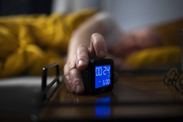 Zeitumstellung, Winterzeit Thema: Schlaf. Mann liegt im Bett und schaltet seinen Wecker ein. Bonn Deutschland *** subject sleep man lies in bed and turns on his alarm clock Bonn Germany Copyright: xUtexGrabowsky photothek.netx