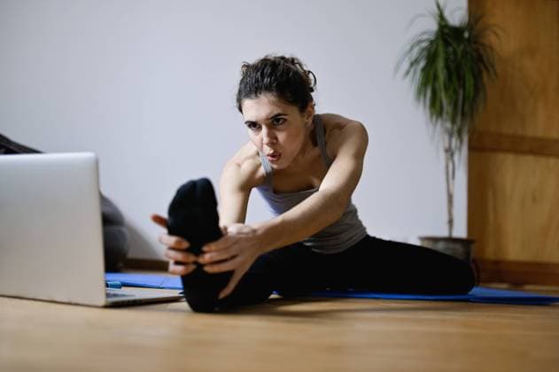 IMAGO Creative, Neujahr, Vorsätze, Sport Adult focused sportswoman leaning forward during workout with video tutorial on netbook at home, Model released Copyright: xCarlosxPintaux MR