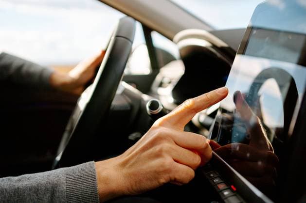IMAGO Creative: Corporate: Klimaschutz, Digitalisierung und Urbanisierung Side view of crop unrecognizable male driver in casual clothes touching screen of GPS navigator while sitting in modern car on sunny day Copyright: xJakexJakabx Model Released