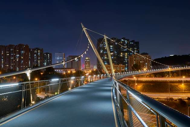 Creative Highlights World Contemporary suspension pedestrian bridge in creative design crossing road in modern urban city at night Copyright: xLuisxGomezx Model Released