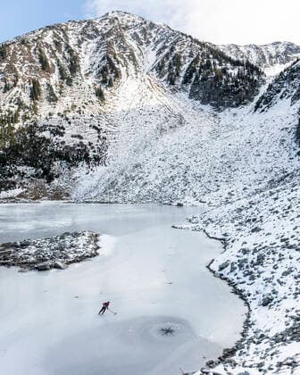 IMAGO Creative, Winter, Winterspaß, Eishockey #2 Drone view of hockey player skating on frozen lake near mountains Canada, British Columbia, Pemberton CR_PSFZ210201-623659-01 ,model released, Symbolfoto