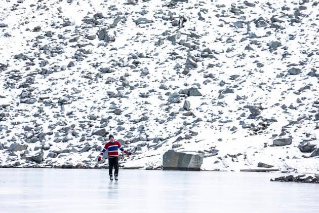 IMAGO Creative, Winter, Winterspaß, Eishockey #2 Full body young hockey player in uniform manouevring puck with stick while riding on ice of frozen lake near stony mountain slope covered with snow in British Columbia, Canada Canada, British Columbia, Pemberton CR_PSFZ210201-623662-01 ,model released, Symbolfoto