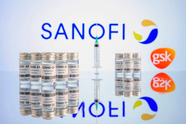 Impfdosen und Impfspritzen stehen auf einem Tisch vor den Logos von Sanofi und GlaxoSmithKline. (Themenbild, Symbolbild)