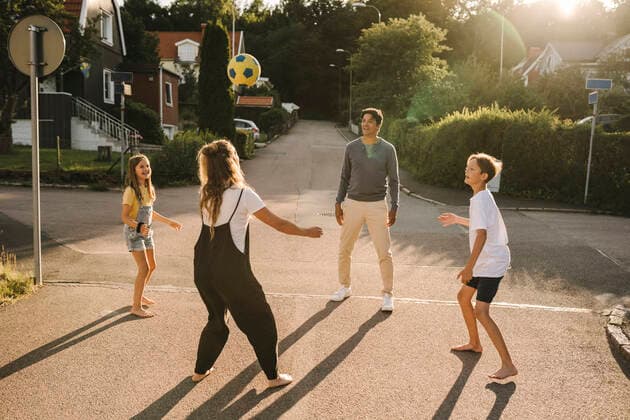Happy family playing with soccer ball on road Sweden, Gothenburg, model released Copyright: xMaskotx , MA83643