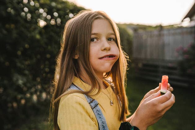 Pre-adolescent girl looking away while eating watermelon in back yard Sweden, Gothenburg, model released Copyright: xMaskotx , MA83653