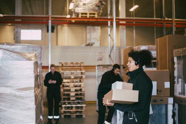 IMAGO Creative: Kreative Renaissance -- der junge Entrepreneur Female entrepreneur holding packages standing by colleagues at logistics warehouse Sweden, Stockholm, model released, property released Copyright: xMaskotx , MA84082