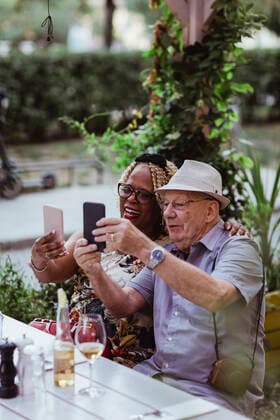 Cheerful senior couple taking selfie on smart phone while sitting in sidewalk cafe Sweden, Stockholm, model released Copyright: xMaskotx , MA84304