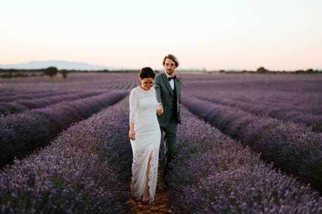 Bride and groom holding hands and walking in blossoming lavender field Copyright: xJakexJakabx Model Released