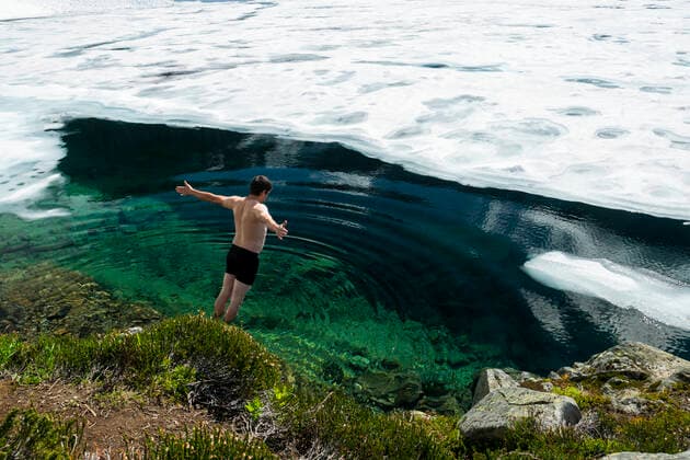 IMAGO Creative: Alternativer Wintersport Back view of shirtless male with outstretched arms falling into cold water of frozen lake on sunny day Canada, British Columbia, Whistler CR_PSFZ210211B-642230-01 ,model released, Symbolfoto