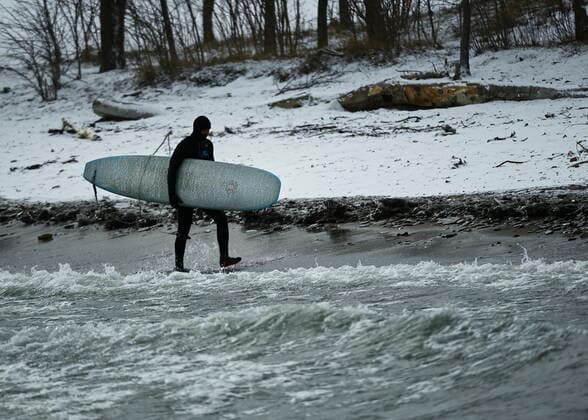 February 12, 2021, Toronto, on, Canada: A man enters the frigid ice cold waters of Lake Ontario with his surf board during the COVID-19 pandemic in Toronto on Friday, February 12, 2021. Toronto Canada  - ZUMAc35_ 20210212_zaf_c35_033 Copyright: xNathanxDenettex