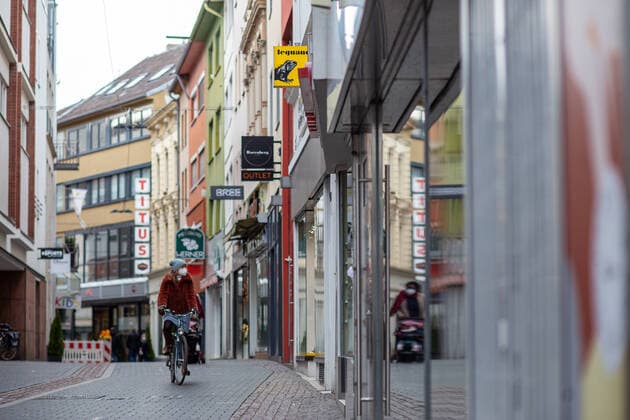 Die Bonner Innenstadt am 16.02.2021. Bonner Innenstadt am 16.02.2021. Foto: Fast Leere Einkaufsstrasse, hier die Acherstraße,Aufgrund der Corona-Pandemie bleiben alle Geschaefte bis voraussichtlich bis ende Februar 2021 geschlossen. Foto: Eine Frau fährt mit dem Fahrrad durch die Acherstraße. Bonn Innenstadt Nordrhein-Westfalen Deutschland