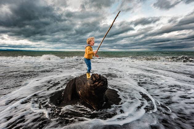 IMAGO Creative: 2021 Favoriten Adventurous child standing on tree in ocean on New Zealand beach Te Awanga, Hawke s Bay, New Zealand CR_JUCR210217-648173-01 ,model released, Symbolfoto