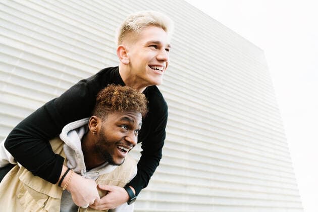 IMAGO Creative: Urban Diversity From below of cheerful young black boy giving piggyback ride to joyful friend while spending time together in city park Copyright: xIoritzxLopezx Model Released