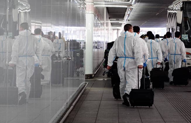21.02.2021, Frankfurt am Main, Hessen, GER - Auswirkungen der Coronapandemie: Flugpassagiere laufen in Schutzanzuegen vor dem Terminal des Flughafen zu einem Reisebus. (Airport, Alltag, Ansteckungsschutz, Asiaten, asiatisch, aussen, Aussenaufnahme, Bus, Chinesen, Coronaepidemie, Coronakrise, Coronapandemie, deutsch, Deutschland, Europa, europaeisch, Flughafen, Flughafenterminal, Flugpassagiere, Flugreisende, Frankfurt, Frankfurt am Main, gehen, Gepaeck, Gesellschaft, Hessen, Koffer, laufen, Menschen, Passagiere, Personen, QF, Querformat, Reise, Reisebus, Reisende, Reisewarnung, schuetzen, Schutz, Schutzanzuege, Terminal, Tourismus, Virenschutz, Vollschutz, warten, Wartezeit, Westeuropa, Wirtschaft) 210221D506FRANKFURT.JPG