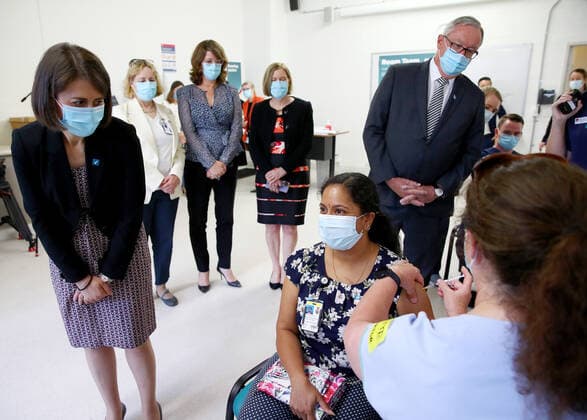 NSW COVID19 VACCINE ROLLOUT, Gayathry Vellangalloor Srinivasan, an Environmental Services Supervisor, is watched by NSW Premier Gladys Berejiklian (left), NSW Chief Medical Health Officer Kerry Chant (second right) and NSW Health Minister Brad Hazzard (right) as she receives the states first Pfizer vaccination at the Royal Prince Alfred Hospital Vaccination Hub in Sydney, Monday, February 22, 2021. Australia will begin its roll out of the Pfizer coronavirus vaccine on Monday, the country s most complicated logistical exercise to date. ( NO ARCHIVING, EDITORIAL USE ONLY, NO USE IN BOOKS WITHOUT CONSENT SYDNEY NSW AUSTRALIA Copyright: xTobyxZernax 20210222001522236356