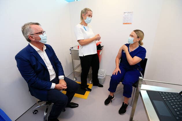 VIC COVID19 VACCINE ROLLOUT, Covid screening nurse Grace Gibney (right) receives one of the first Pfizer coronavirus vaccines from Nurse practitioner Sonja Elia as Health Minister Martin Foley (left) watches on at Austin Health in Melbourne, Monday, February 22, 2021. Australia will begin its roll out of the Pfizer coronavirus vaccine on Monday, the country s most complicated logistical exercise to date. ( NO ARCHIVING, EDITORIAL USE ONLY, NO USE IN BOOKS WITHOUT CONSENT MELBOURNE VIC AUSTRALIA  Copyright: xMARKxSTEWARTx 20210222001522293459