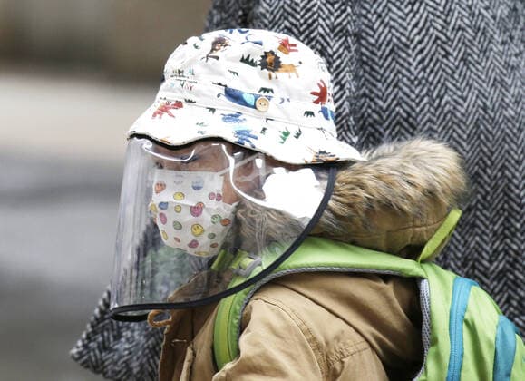 A child walks wearing a face mask and face shield to protect from and to prevent the spread of the coronavirus on Wall Street in New York City on Monday February 22, 2021. COVID-19 deaths have now surpassed the 500,000 mark in the United States.  NYP20210222105 JohnxAngelillo