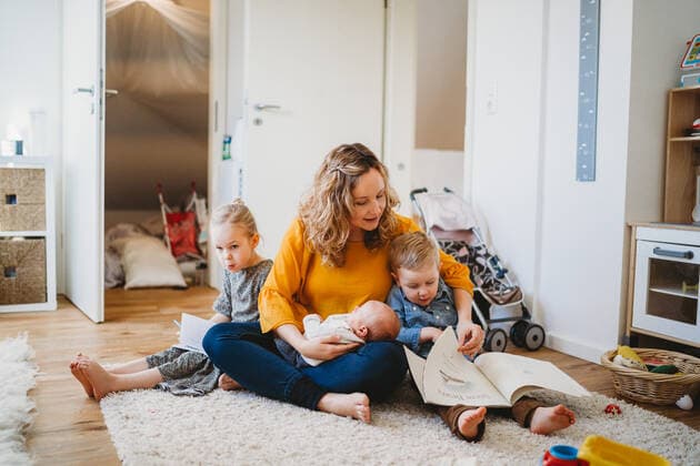 IMAGO Creative: Kulturelle Folgen der Pandemie: Gesundheitsbewußtsein und Alleinsein IMAGO Creative: Jahreszeit Winter, Fantasievoll drinnen spielen White mother hugging children reading books sitting on rug at home Munich, BY, Germany CR_TANI210222B-601451-01 ,model released, Symbolfoto
